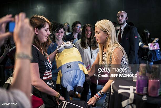 French blogger Marie Lopez, aka EnjoyPhoenix, receives a soft toy as a gift during a signing of her first book "Enjoy Marie" on June 17, 2015 in a...