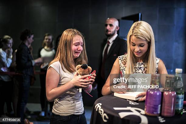 French blogger Marie Lopez, aka EnjoyPhoenix, stands by a crying fan who offers her a soft toy during a signing of her first book "Enjoy Marie" on...