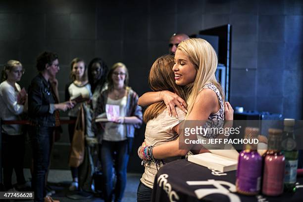 French blogger Marie Lopez, aka EnjoyPhoenix, gives a hug to a fan during a signing of her first book "Enjoy Marie" on June 17, 2015 in a cultural...
