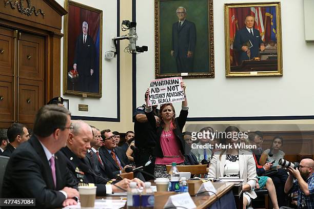Protester holds up a sign while Defense Secretary Ashton Carter and Chairman of the Joint Chiefs of Staff Gen. Martin Dempsey testify before the...