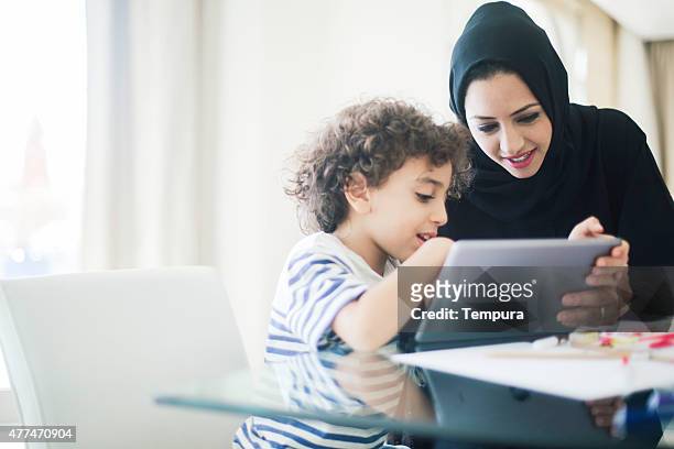 middle eastern mutter hilft ihr kind bei den hausaufgaben. - emirate family stock-fotos und bilder