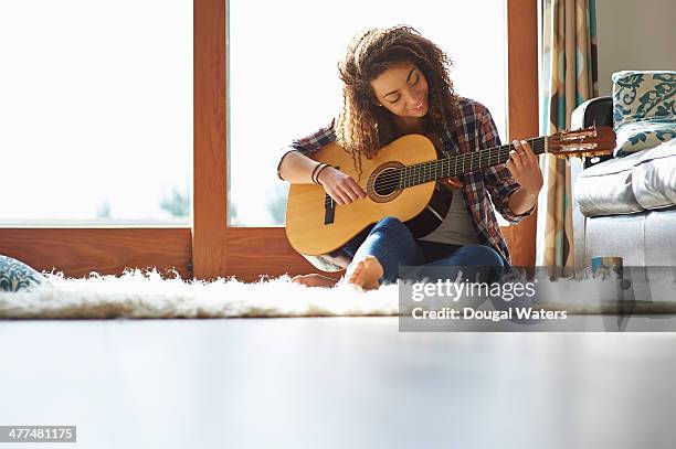 woman playing guitar in lounge. - woman acoustic guitar stock pictures, royalty-free photos & images