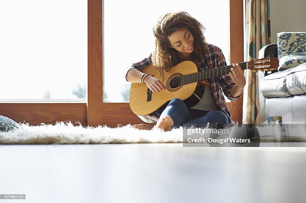 Woman playing guitar in lounge.
