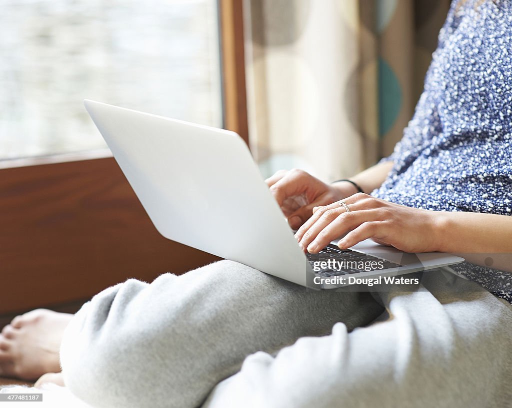 Woman using laptop at home, close up.