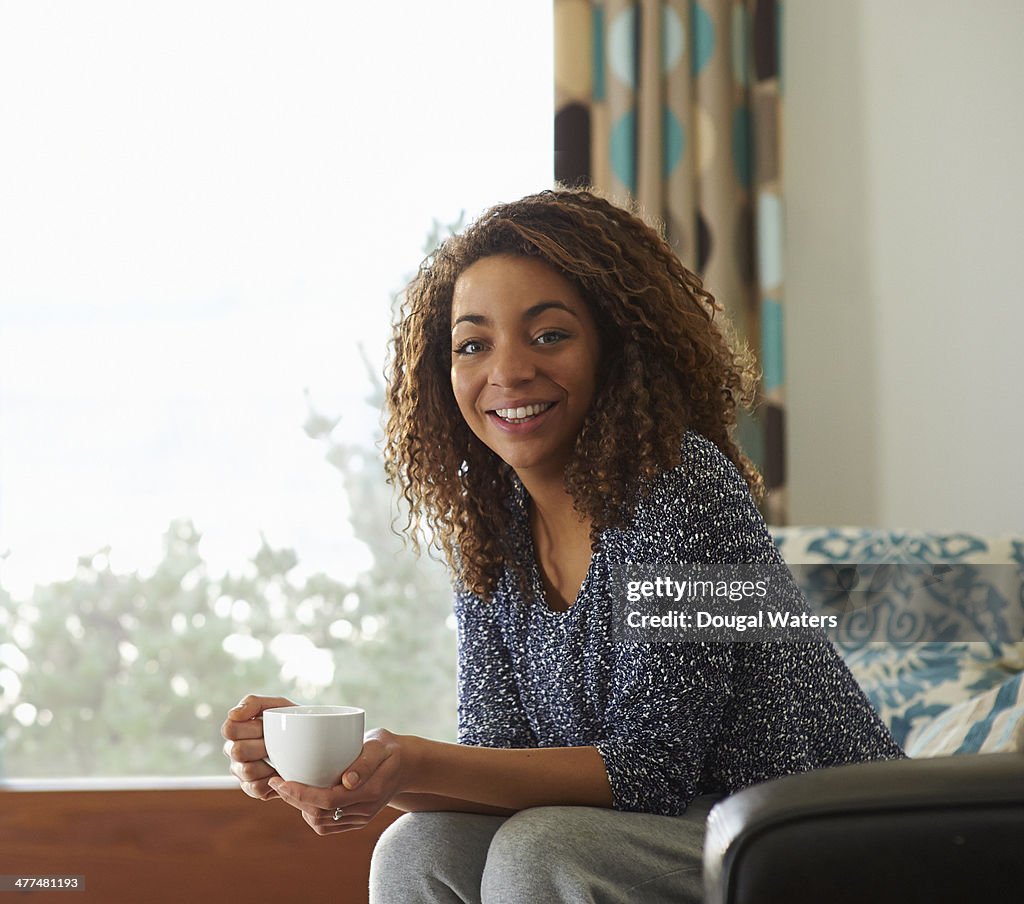 Woman sitting with drink in lounge.