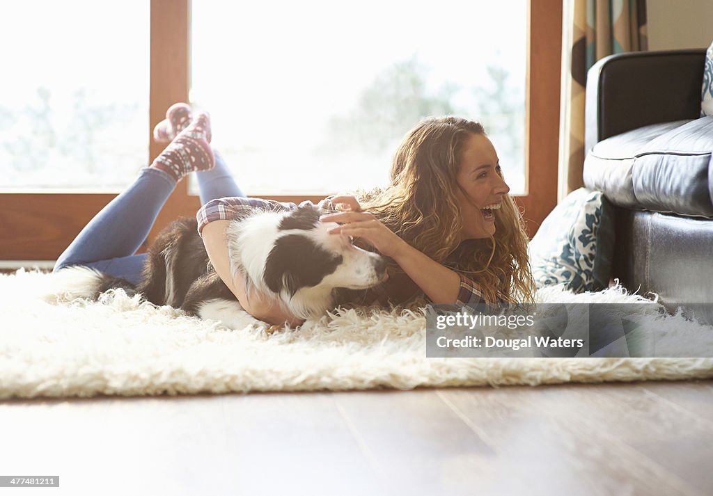 Woman playing with dog at home.