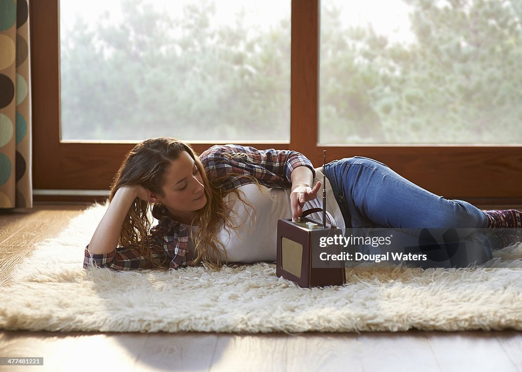 Woman listening to old radio in lounge.