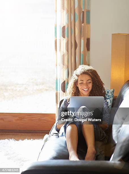 woman sitting on sofa using laptop. - netbook stock-fotos und bilder