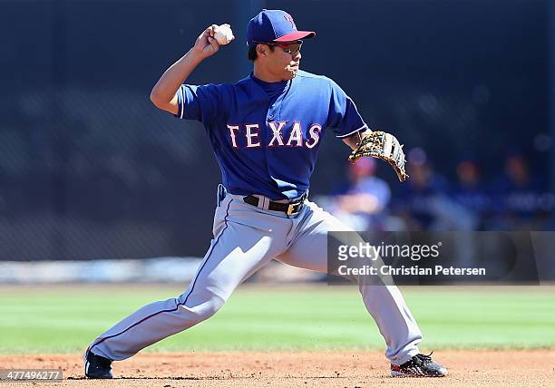 Infielder Kensuke Tanaka of the Texas Rangers fields a ground ball out against the Seattle Mariners during the first inning of the the spring...