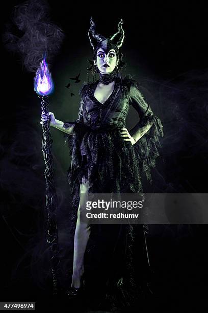 evil sorceress in black gown and magic staff - herdersstaf stockfoto's en -beelden