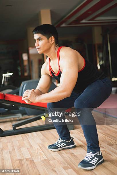 young man doing squats in a gym - lowering stockfoto's en -beelden
