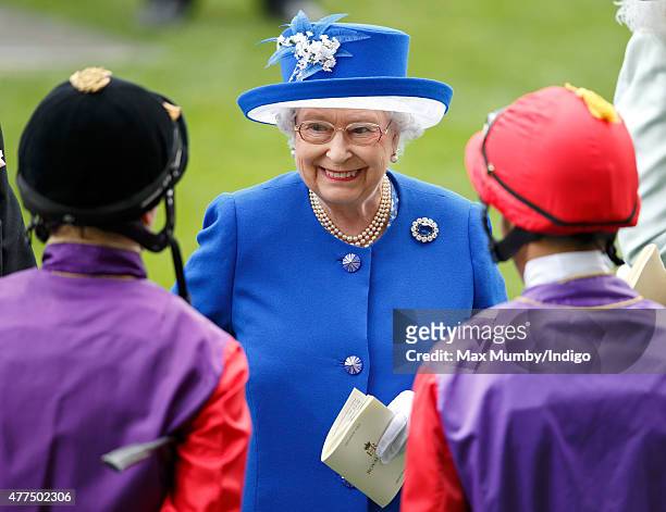 Queen Elizabeth II talks with jockeys Jamie Spencer and Sean Levey prior to them riding her horses 'Touchline' and 'Pack Together' in The Sandringham...
