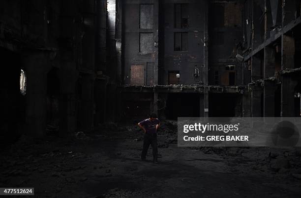 This photo taken on June 4, 2015 shows a worker walking through an abandoned and partly demolished building, its floor covered in black soot, at the...