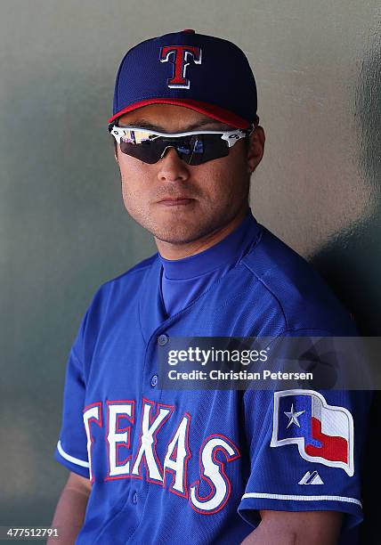 Kensuke Tanaka of the Texas Rangers sits in the duogut during the spring training game against the Los Angeles Dodgers at Surprise Stadium on March...