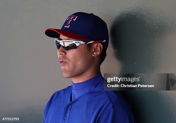 Kensuke Tanaka of the Texas Rangers sits in the duogut during the spring training game against the Los Angeles Dodgers at Surprise Stadium on March...