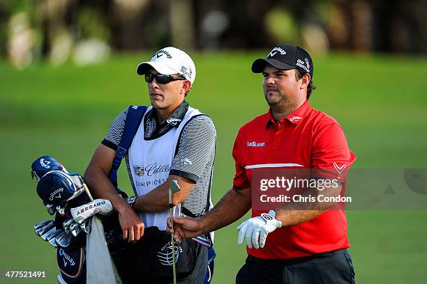 Patrick Reed hands his club to his caddie Kessler Karin while playing on the 12th hole during the final round of the World Golf...