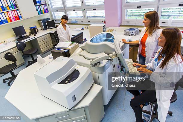 three cute technicians in laboratory of blood bank - test tube rack stock pictures, royalty-free photos & images