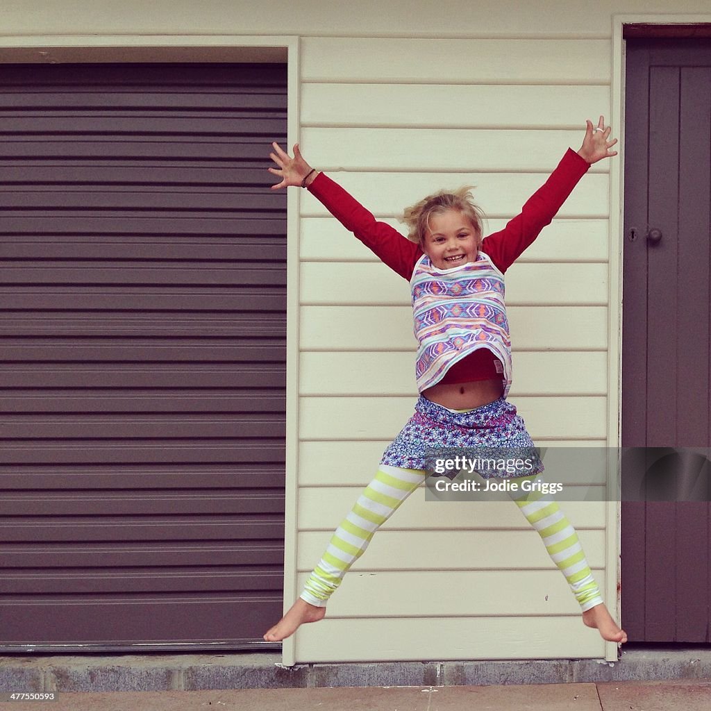 Happy child outside doing a star jump