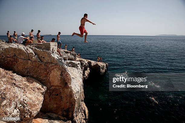 Bather leaps from a rock into the sea on the coast south west of Athens, Greece, on Monday, June 15, 2015. The tourism industry contributes 17...