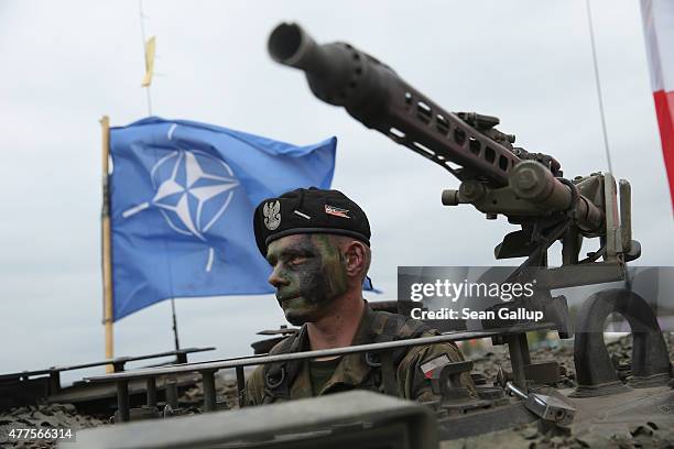 Soldier of the Polish Army sits in a tank as a NATO flag flies behind during the NATO Noble Jump military exercises of the VJTF forces on June 18,...