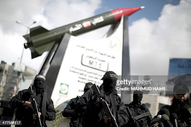 Palestinian militants of the Ezzedine al-Qassam Brigades, Hamas's armed wing, stand in front of a model of a Gaza Strip made M75 rocket newly...