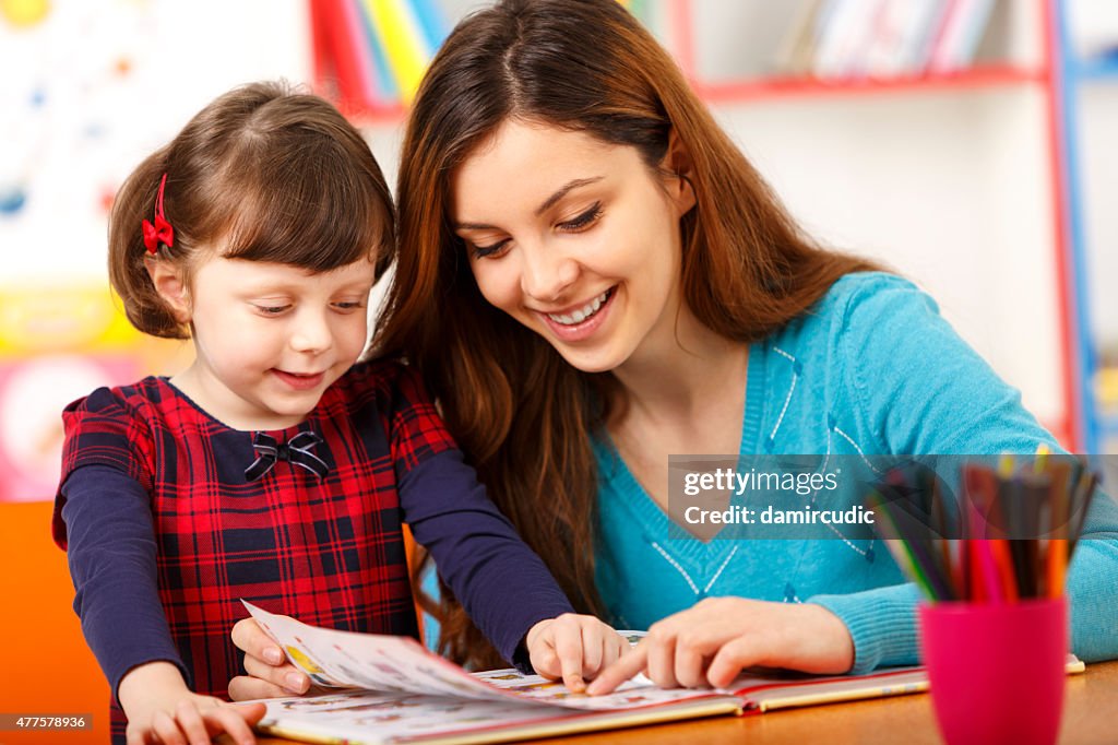 Child reading with a preschool teacher