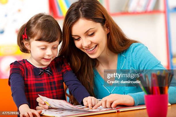 child reading with a preschool teacher - free childcare stock pictures, royalty-free photos & images