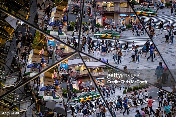 People are seen reflected in a shopping mall mirror at a busy intersection in the shopping district of Harajuku on June 18, 2015 in Tokyo, Japan.