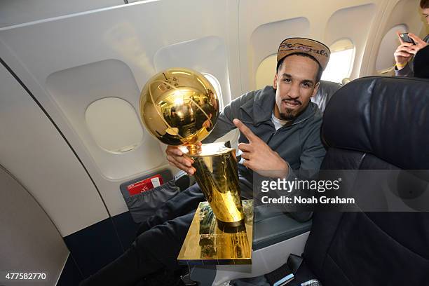 Shaun Livingston of the Golden State Warriors holds the NBA trophy on the plane as the team travels home from Cleveland after winning the 2015 NBA...