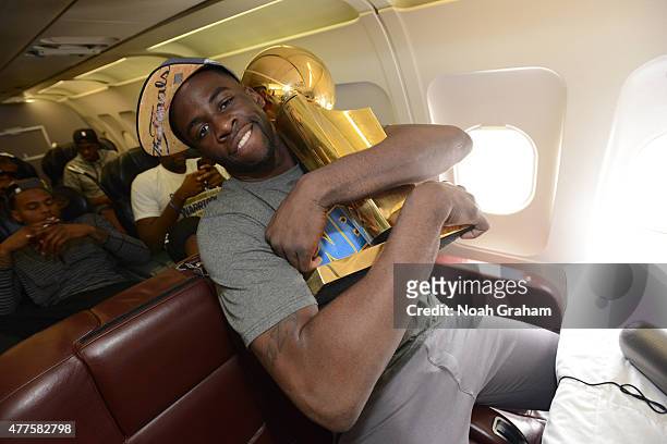 Draymond Green of the Golden State Warriors holds the NBA trophy on the plane as the team travels home from Cleveland after winning the 2015 NBA...