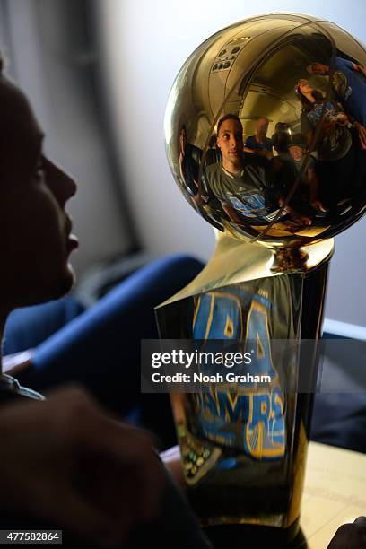 Stephen Curry of the Golden State Warriors holds the NBA trophy on the plane as the team travels home from Cleveland after winning the 2015 NBA...