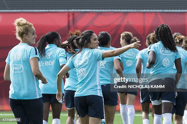 France s Louisa Necib points out her mother watching from the stands to teammate Kheira Hamraoui during a training session in Ottawa on June 18, 2015...