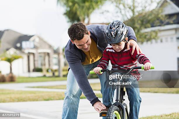 learning to ride bicycle - father helping son wearing helmet stock pictures, royalty-free photos & images