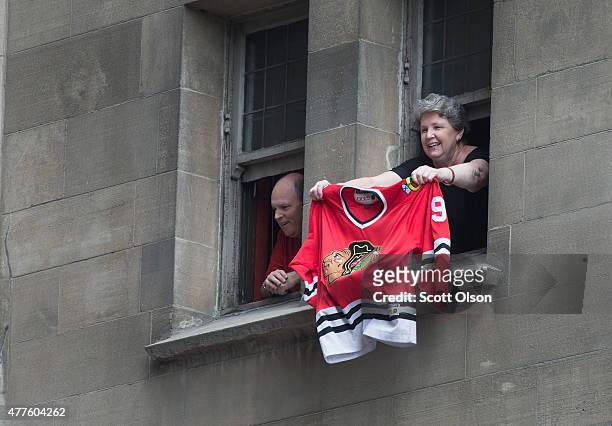 Fan waves a Blackhawks jersey from a building as people pack the streets below to watch a parade held to celebrate the Chicago Blackhawks' winning of...