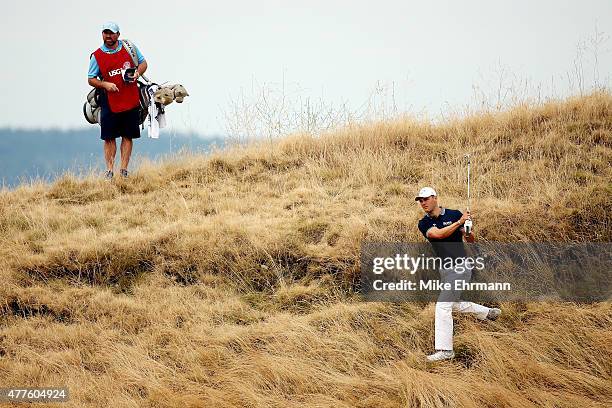 Martin Kaymer of Germany plays a shot from the rough on the 13th hole as his caddie Craig Connelly looks on during the first round of the 115th U.S....