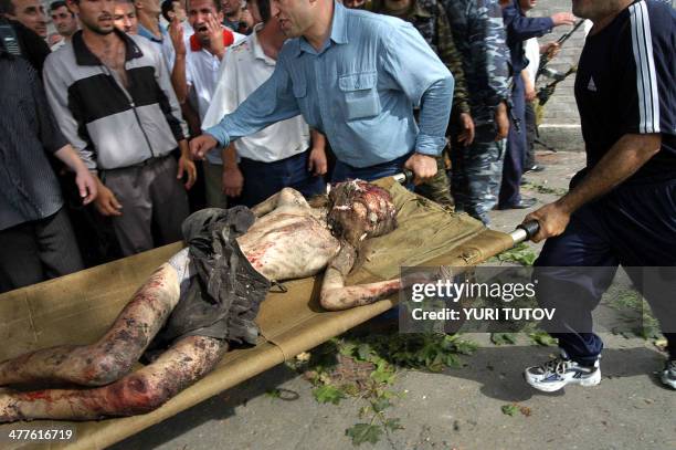 Ossetian volunteers carry a stretcher with injured boy in the school garden during the attack operation in the town of Beslan, North Ossetia, 03...