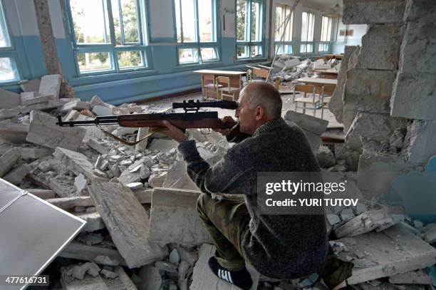 An Ossetian militiaman aims from a boarding school, at the opposite school, where a group of gunmen, wearing belts laden with explosives, are holding...