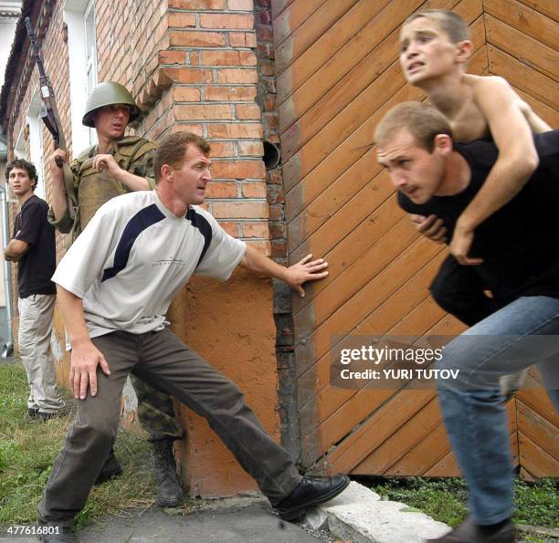 Man carries a boy, hostage as a soldier and volunteer stand behind a school fence during the rescure operation in the town of Beslan, North Ossetia....