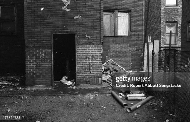 View of garbage strewn yard and boarded up windows in an apartment building in the Englewood neighborhood, Chicago, Illinois, 1968.