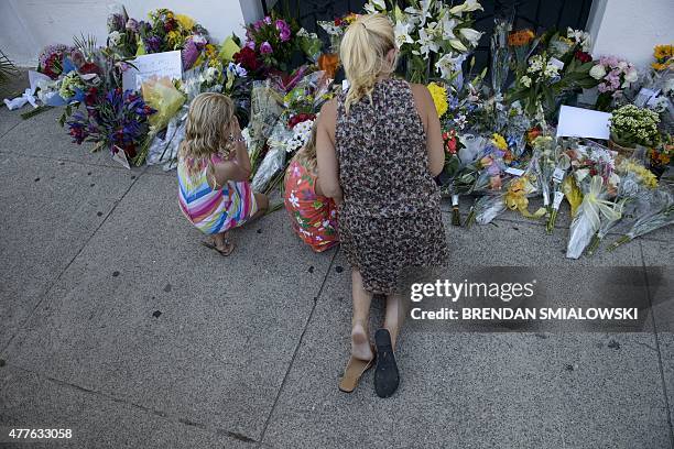 Mourners gather at a makeshift memorial outside the Emanuel AME Church June 18, 2015 in Charleston, South Carolina, after four pastors, a librarian...