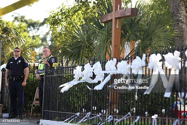Charleston police officers stand near a fence that nine ribbons were hung in front of the Emanuel African Methodist Episcopal Church after a mass...