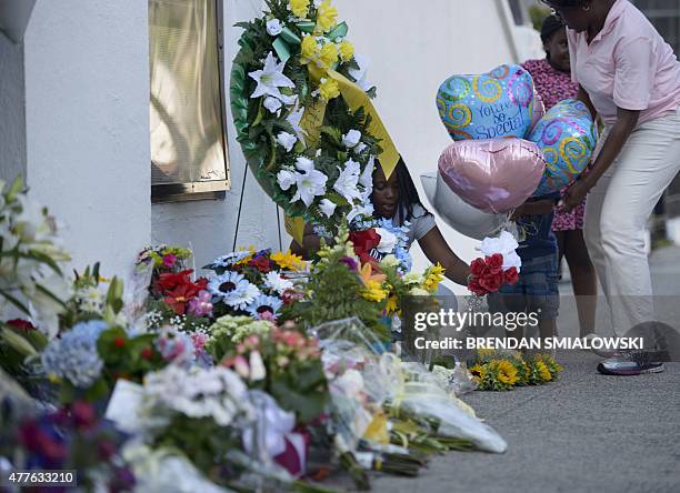 Mourners gather at a makeshift memorial outside the Emanuel AME Church June 18, 2015 in Charleston, South Carolina, where nine people were shot dead...