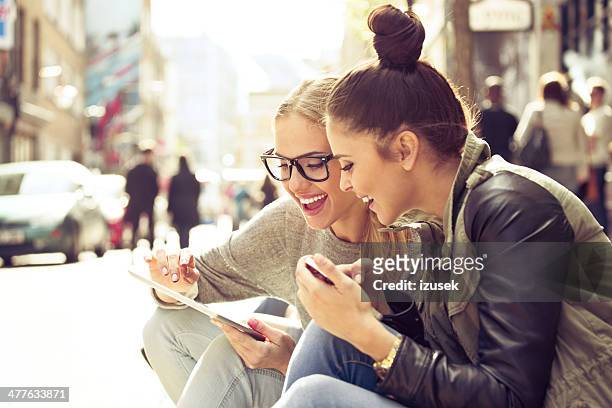 deux jeunes femmes avec tablette dans la rue - vie londres soleil photos et images de collection