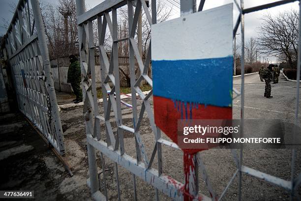 Members of the new pro-Russian forces dubbed the "military forces of the autonomous republic of Crimea" stand at the gate, adorned with a Russian...