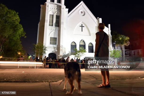 Woman pauses in respect as she passes next to Emanuel AME Church in Charleston, South Carolina on June 18, 2015. Police captured the white suspect in...