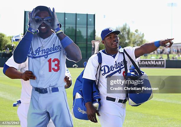 Yasiel Puig of the Los Angeles Dodgers walks alongside Juan Uribe as he carries a life size photo of Hanley Ramirez before the spring training game...