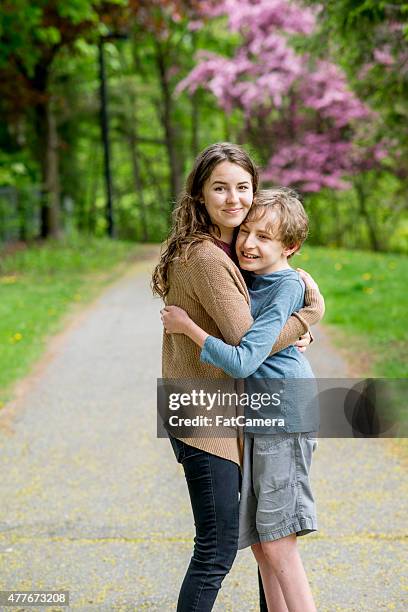 brother and sister embracing in the park - developmental disability stock pictures, royalty-free photos & images