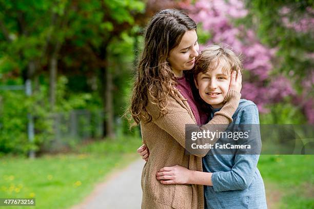 sister embracing younger brother - learning disability nurse stock pictures, royalty-free photos & images