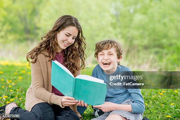 brother and sister reading in the park - learning disability nurse stock pictures, royalty-free photos & images