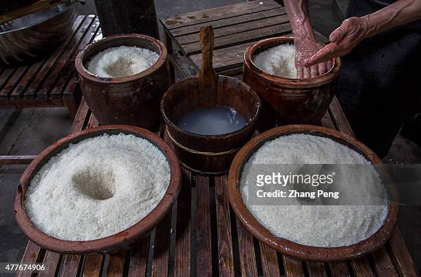 In a traditional workshop, craftsmen dig a hole in the cooked rice. The rice wine will be fermented and converge in the hole. Rice wine, also known...